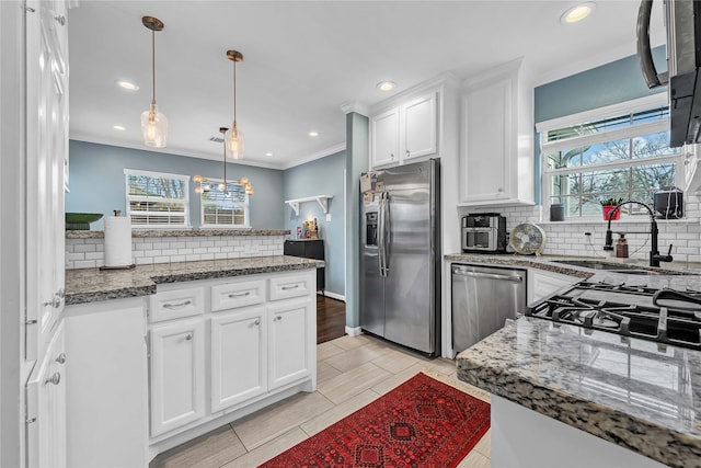 kitchen featuring white cabinetry, sink, decorative light fixtures, and stainless steel appliances