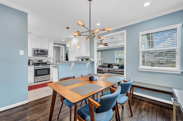 dining area featuring ornamental molding, ceiling fan with notable chandelier, and dark hardwood / wood-style floors