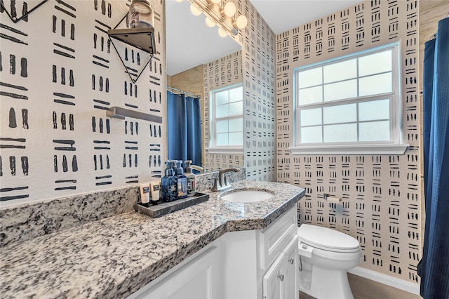 bathroom with walk in shower, vanity, and toilet