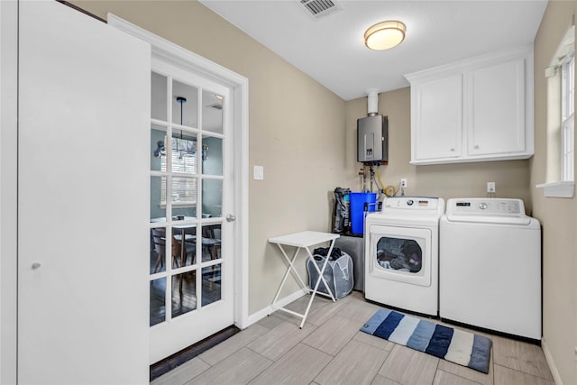 washroom with tankless water heater, cabinets, and separate washer and dryer