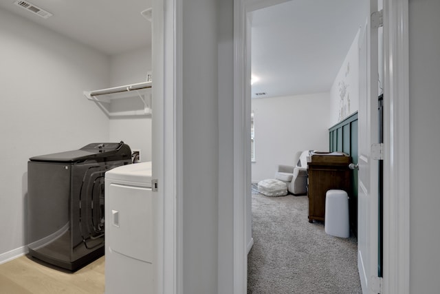 laundry area with washer and clothes dryer, light carpet, baseboards, visible vents, and laundry area