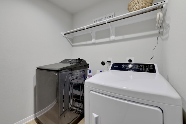 washroom with laundry area, washing machine and dryer, and baseboards