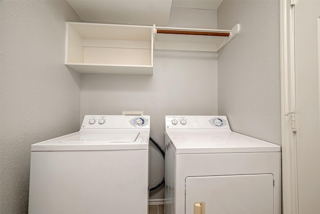 washroom with laundry area, a textured wall, and washing machine and dryer