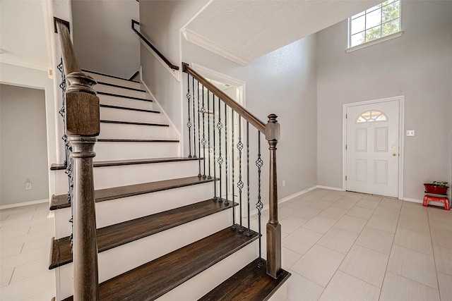 foyer featuring ornamental molding, baseboards, and stairs