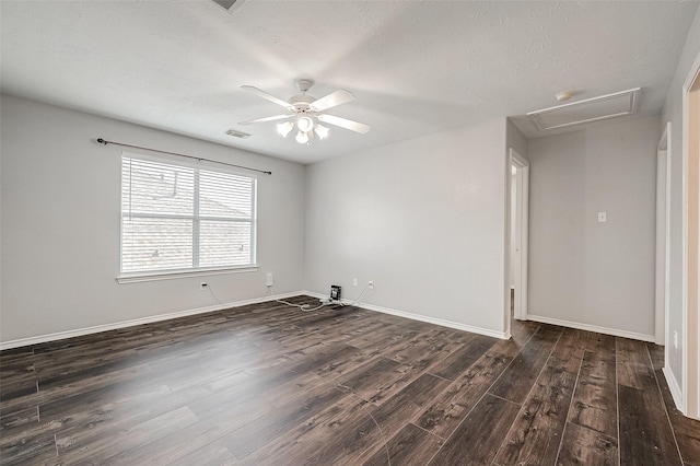 unfurnished room featuring baseboards, a ceiling fan, dark wood-style flooring, and attic access