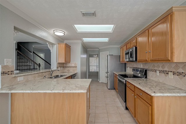 kitchen featuring light stone counters, a sink, light tile patterned floors, appliances with stainless steel finishes, and a peninsula