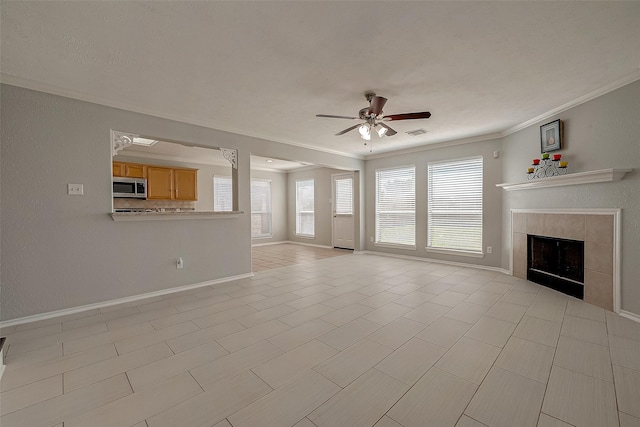 unfurnished living room with crown molding, a ceiling fan, baseboards, visible vents, and a fireplace