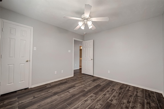 empty room featuring ceiling fan, baseboards, and dark wood-style floors