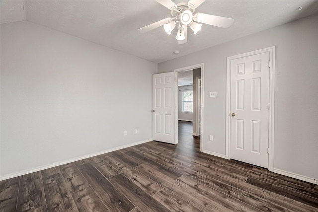 unfurnished bedroom featuring baseboards, a ceiling fan, dark wood-style flooring, and a textured ceiling