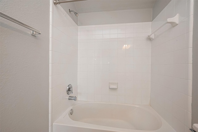 bathroom with bathtub / shower combination and a textured wall