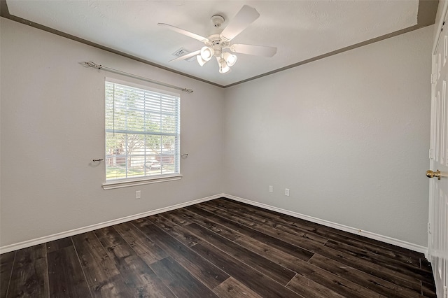 spare room featuring a ceiling fan, baseboards, ornamental molding, visible vents, and dark wood-type flooring