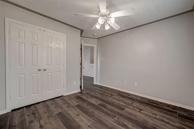 unfurnished bedroom featuring baseboards, ornamental molding, ceiling fan, a closet, and dark wood-type flooring