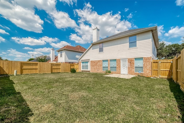 rear view of house with a patio area, a gate, a yard, brick siding, and a fenced backyard