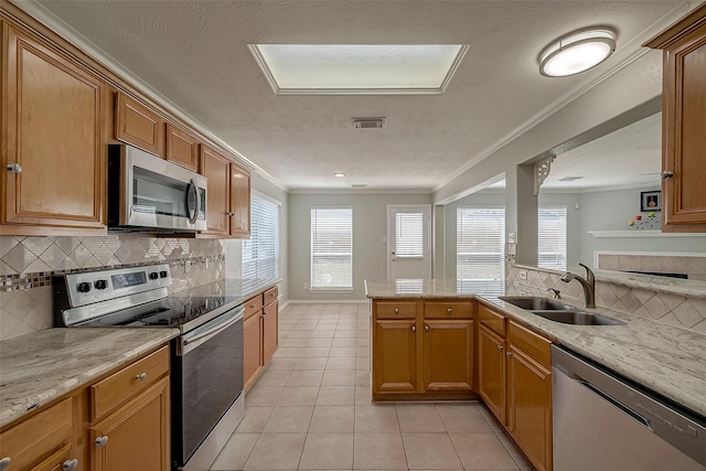 kitchen featuring ornamental molding, a sink, light tile patterned floors, appliances with stainless steel finishes, and a peninsula