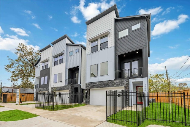 view of front facade featuring stone siding, a fenced front yard, driveway, stucco siding, and an attached garage