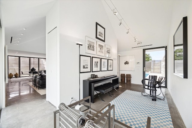 interior space featuring high vaulted ceiling, concrete flooring, and track lighting