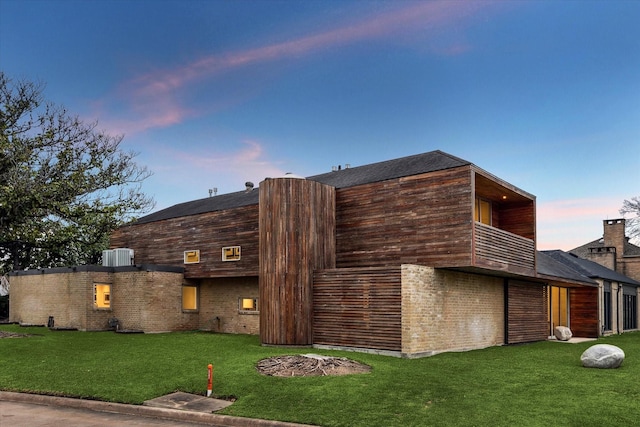 exterior space featuring central AC, a yard, a balcony, and brick siding