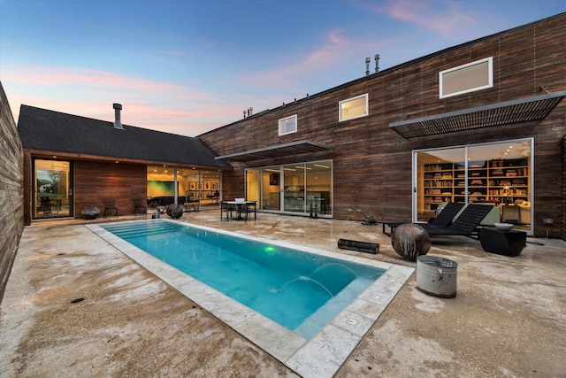 pool at dusk featuring a patio and an outdoor pool