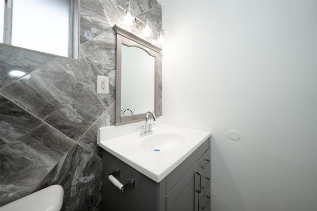 half bath featuring vanity, toilet, and tile walls