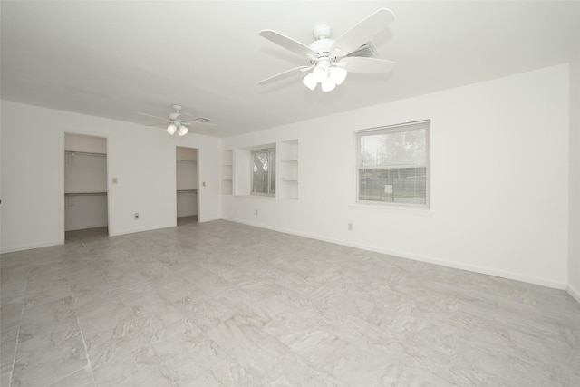 unfurnished bedroom with baseboards, ceiling fan, and two closets