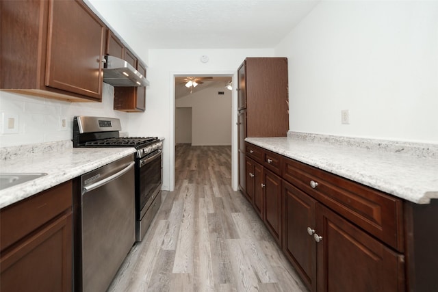 kitchen featuring appliances with stainless steel finishes, light wood-style flooring, light stone countertops, ceiling fan, and under cabinet range hood