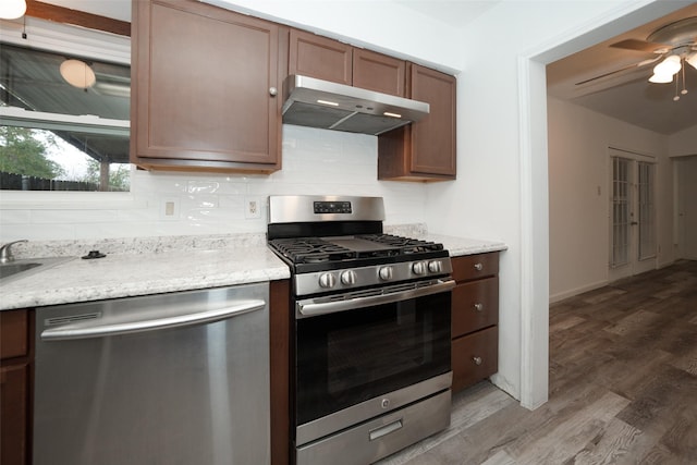 kitchen with tasteful backsplash, appliances with stainless steel finishes, dark wood finished floors, and under cabinet range hood