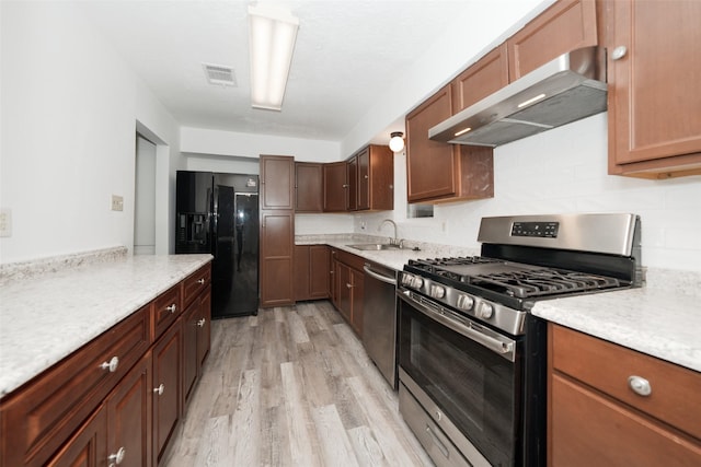 kitchen with a sink, wall chimney range hood, visible vents, appliances with stainless steel finishes, and light wood-type flooring