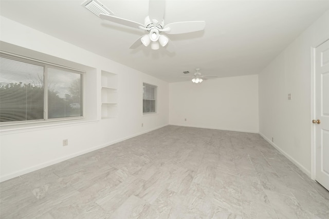 spare room featuring built in shelves, visible vents, baseboards, and ceiling fan