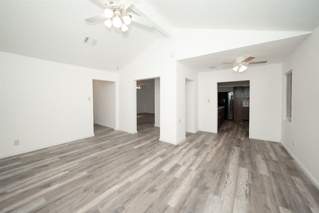 empty room featuring visible vents, ceiling fan, lofted ceiling with beams, and light wood-style flooring