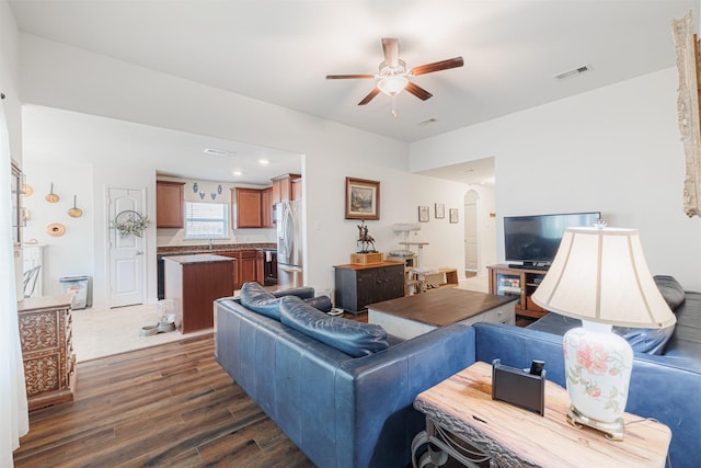 living area featuring a ceiling fan, dark wood-style floors, arched walkways, and visible vents