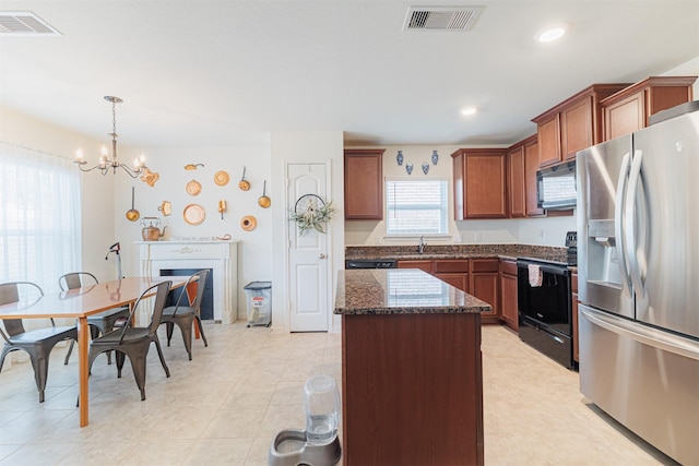 kitchen featuring visible vents, a center island, dark stone countertops, decorative light fixtures, and black appliances