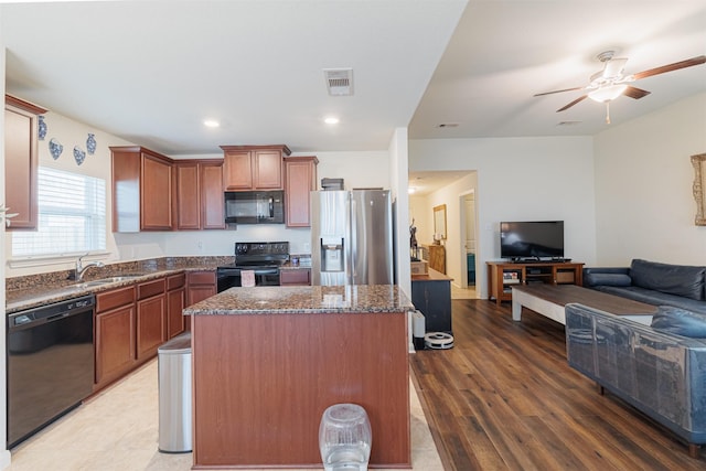 kitchen with a center island, open floor plan, visible vents, a sink, and black appliances