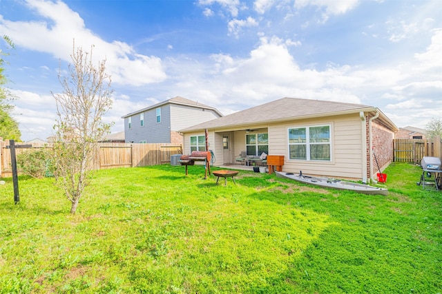 rear view of property featuring brick siding, a lawn, a fenced backyard, and a patio