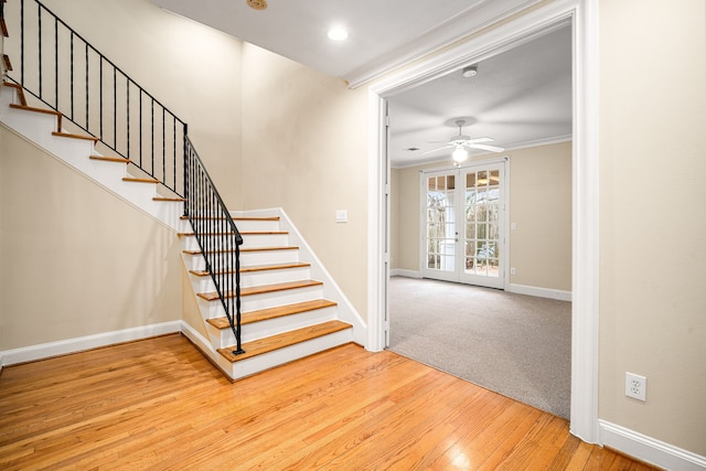 stairway featuring baseboards, crown molding, wood finished floors, a ceiling fan, and french doors