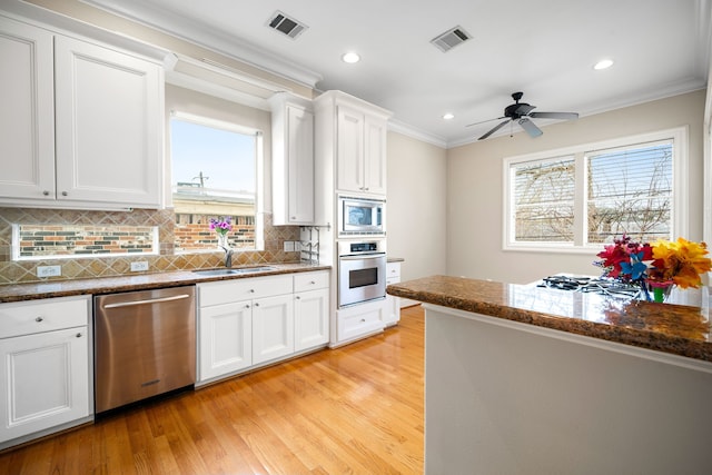 kitchen with a sink, white cabinets, appliances with stainless steel finishes, and dark stone counters