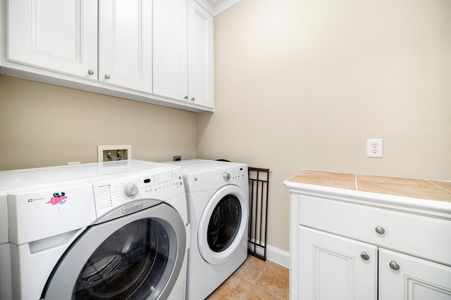 laundry area featuring baseboards, separate washer and dryer, light tile patterned floors, and cabinet space