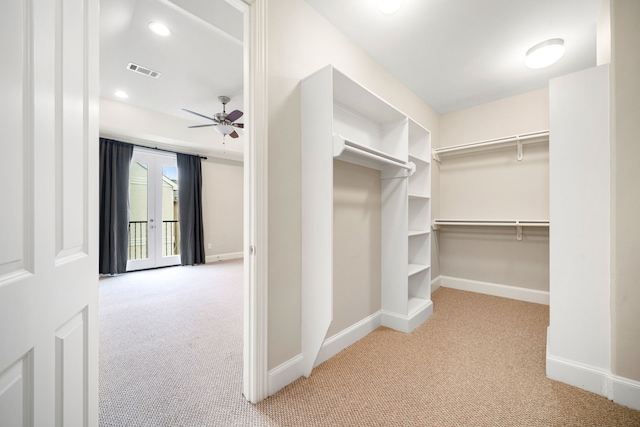 spacious closet with a ceiling fan, visible vents, and light carpet