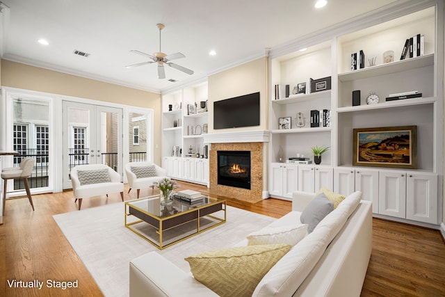 living room with french doors, light wood-style flooring, and crown molding