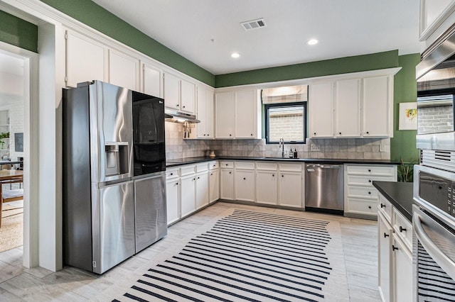 506 Fox Briar Ln, Sugar Land, TX 77478 - kitchen featuring stainless steel appliances, a sink, under cabinet range hood, dark countertops, and tasteful backsplash
