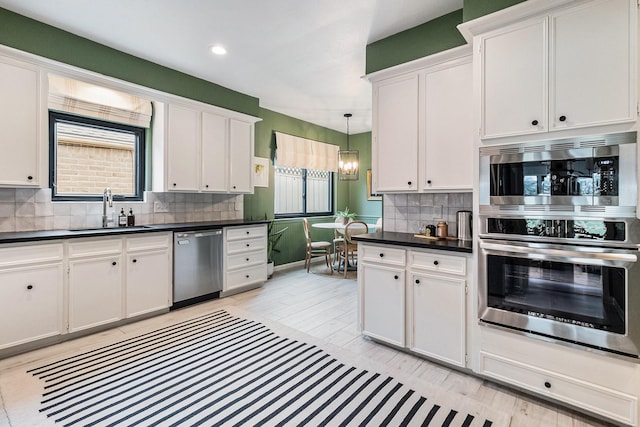 506 Fox Briar Ln, Sugar Land, TX 77478 - kitchen with stainless steel appliances, a sink, dark countertops, white cabinets, and tasteful backsplash