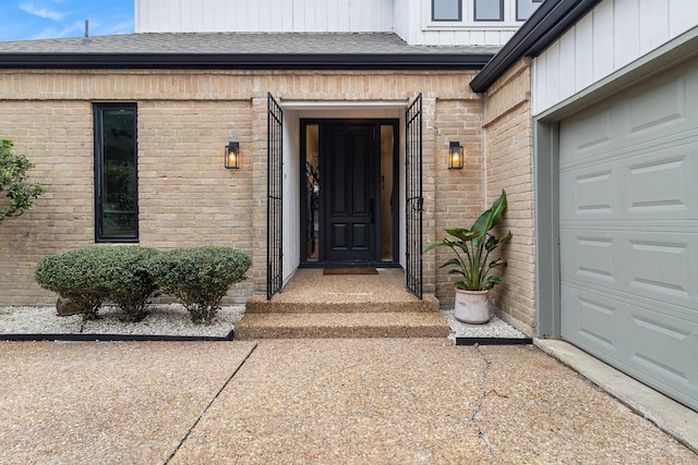 doorway to property featuring brick siding, board and batten siding, a shingled roof, and concrete driveway