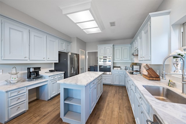 kitchen with a sink, appliances with stainless steel finishes, a center island, white cabinets, and open shelves