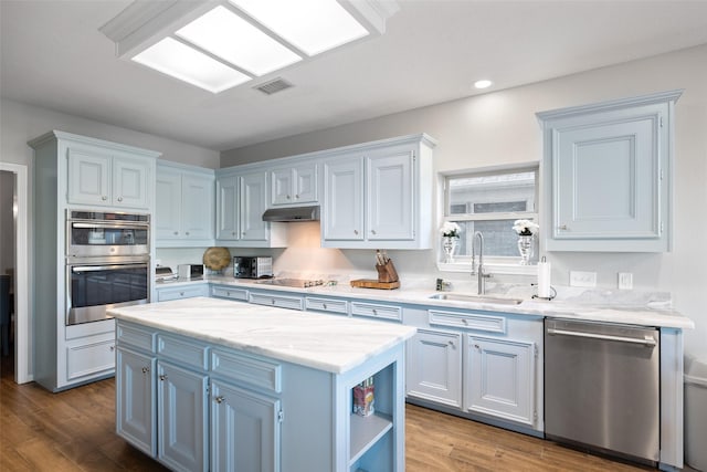 kitchen featuring a center island, a sink, open shelves, under cabinet range hood, and appliances with stainless steel finishes