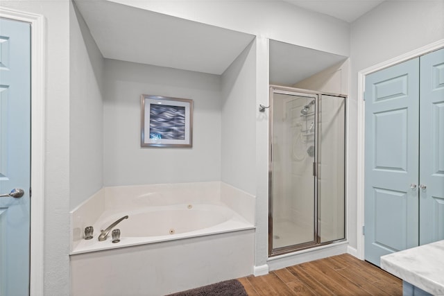 bathroom featuring a jetted tub, wood finished floors, and a shower stall