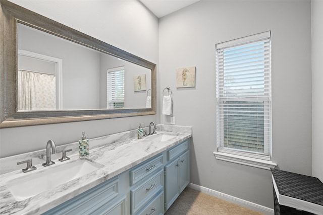 full bathroom with a sink, baseboards, and double vanity