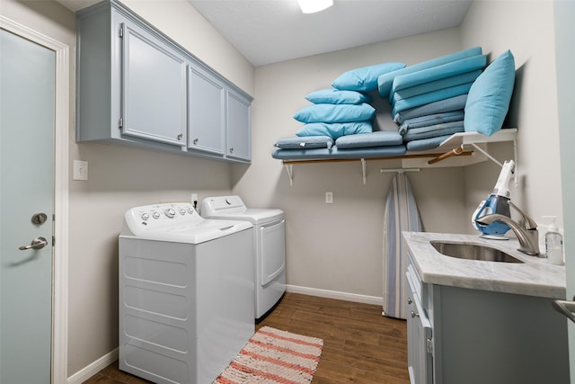 laundry area featuring a sink, dark wood-style floors, washer and clothes dryer, baseboards, and cabinet space