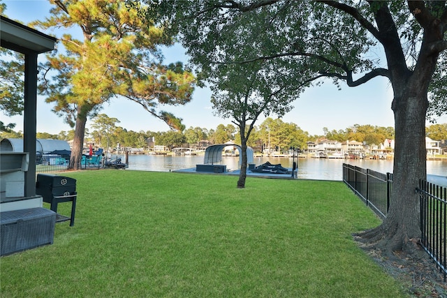 view of yard featuring a water view, a boat dock, and fence