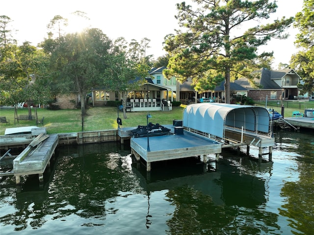 dock area featuring a water view, fence, a lawn, and boat lift