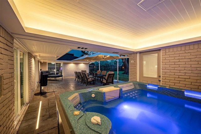 game room featuring brick wall, a tray ceiling, and a hot tub