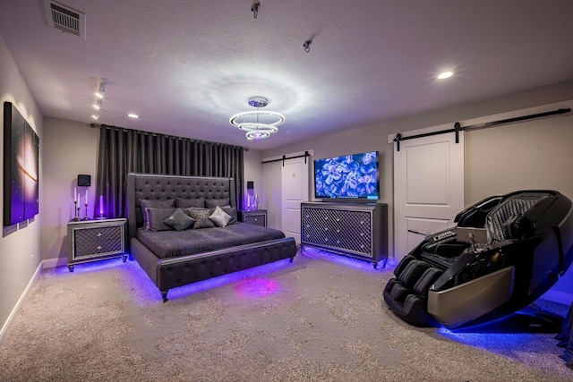 bedroom with visible vents, carpet, a textured ceiling, and a barn door